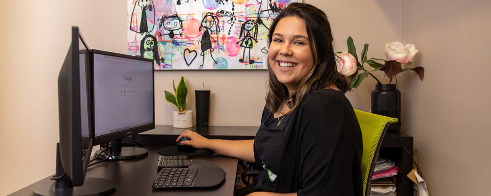 A female educator sits at a computer, and smiles towards the camera. Text on the left reads 'Free access until end of January 2022'.